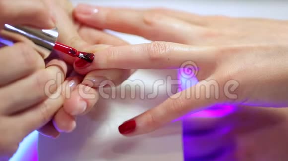 美容师把红色指甲油涂在年轻女性的指甲上视频的预览图