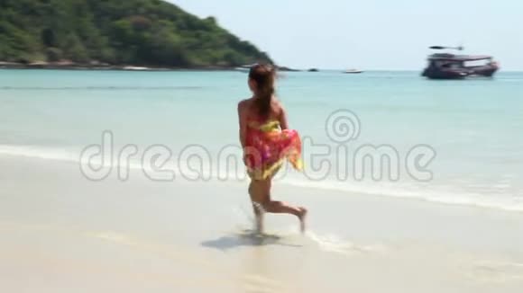 那个女孩在沙滩上跑步它发展到相机微笑和挥手一只手视频的预览图