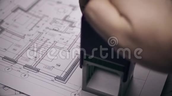 男人手臂在房子的平面图上贴上印戳背景上模糊的房屋蓝图视频的预览图