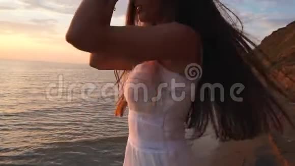 一个穿着白裙子的女孩在海滩上跳舞视频的预览图