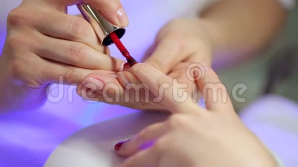 美容师把红色指甲油涂在年轻女性的指甲上视频的预览图