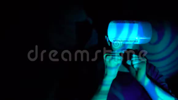 年轻帅哥在聚光灯下戴着虚拟现实头盔做武术动作视频的预览图