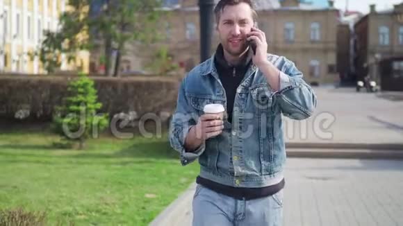一个穿着休闲服的男人走在街上在咖啡休息时打电话视频的预览图