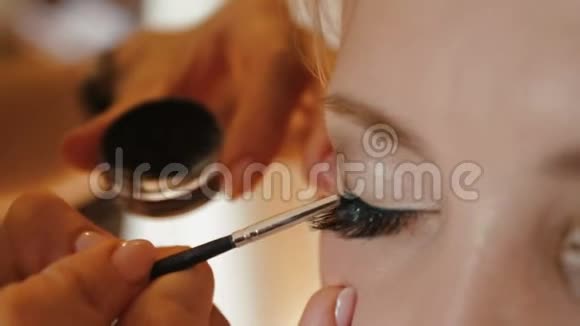 化妆师正在为迷人的新娘化妆她在画猫眼睛准备婚礼视频的预览图