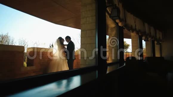 迷人的一对新婚夫妇在露台上温柔地拥抱新娘正在亲吻她的情人的头视频的预览图