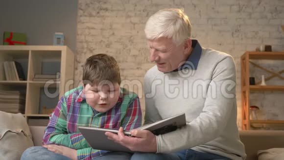 老人教一个年轻的胖子如何阅读祖父和孙子幸福的家庭家庭舒适的概念60英尺视频的预览图