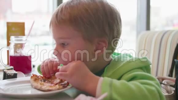 一个小孩子在快餐店吃披萨带有奶酪火腿西红柿和香草的比萨视频的预览图