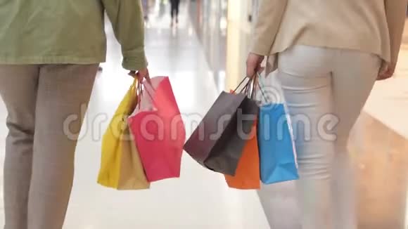 一群购物狂拿着购物袋在商场里走来走去慢动作在购物中心散步的女性视频的预览图