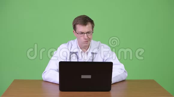 青年医生坐着用笔记本电脑思考的画像视频的预览图