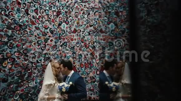 可爱优雅的新婚夫妇温柔地拥抱在五颜六色的墙上视频的预览图