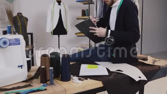 一位时装设计师坐在阁楼的桌子上画草图来裁剪新的服装系列A视频的预览图