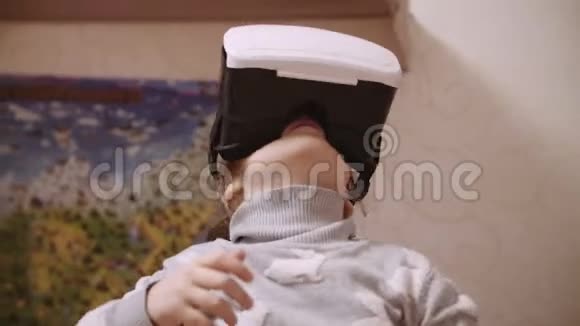 小女孩在VR耳机上抬头试图触摸虚拟现实中的物体在家里室内视频的预览图