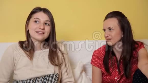 两个年轻女孩坐在家里的沙发上雨天看着一部喜剧谈笑风生晚上回家舒适视频的预览图