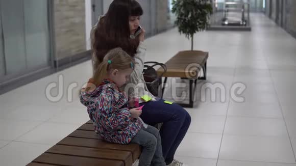 一个女商人在商场里检查她的记录女儿在等妈妈视频的预览图