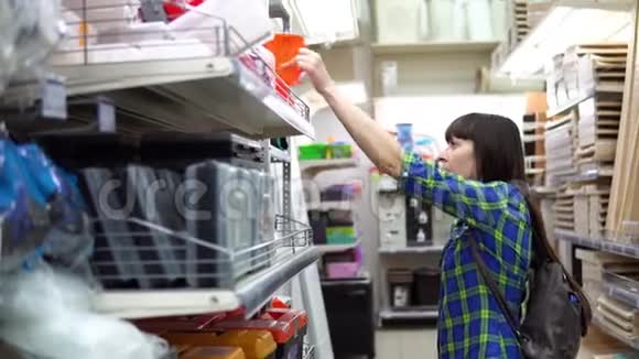 一个年轻的女人在一家建筑超市里选择了一个小橙色的容器视频的预览图