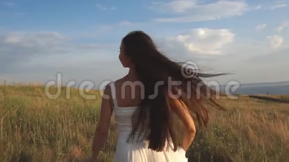 在一个阳光明媚的日子里一个女人走在麦田里穿着一件白色的衣服背景是大自然视频的预览图