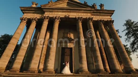 迷人优雅的新婚夫妇正在巴洛克风格的旧建筑附近跳舞和接吻视频的预览图