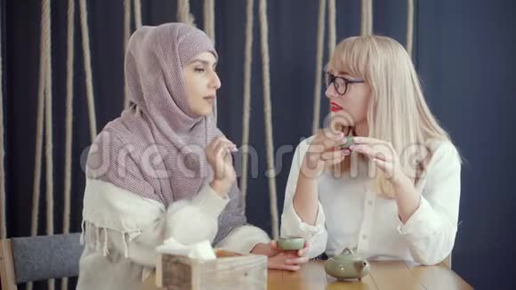 两位穆斯林和高加索妇女在咖啡馆里聊天喝茶视频的预览图
