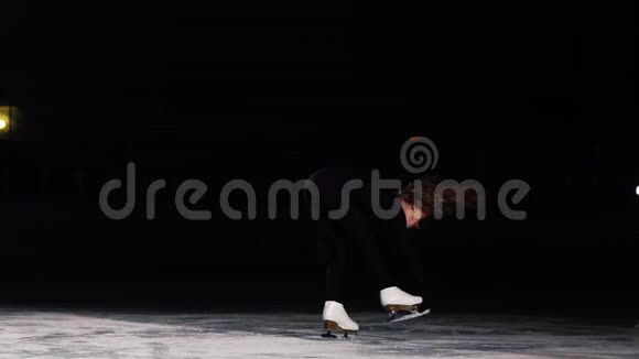 小女孩滑冰运动员站在冰场的竞技场上旋转用一只手握着溜冰鞋视频的预览图