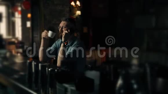 英俊的小胡子站着在咖啡馆里打电话喝咖啡视频的预览图