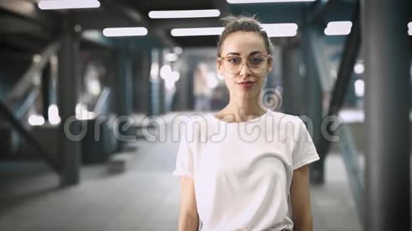 年轻的微笑时尚的美女戴着透明的眼镜摆在户外慢动作视频的预览图
