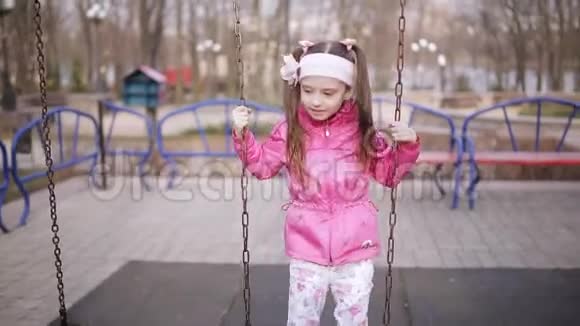可爱的小女孩在春天公园荡秋千视频的预览图
