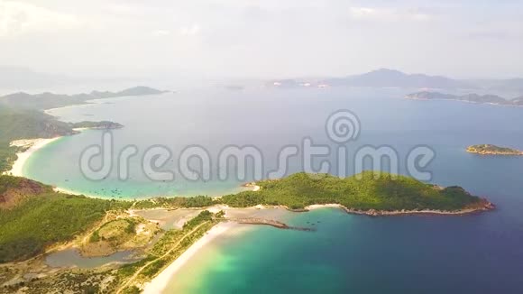 从飞行无人机可以看到海湾和绿色岛屿蔚蓝的大海沙滩和天际线上的绿色岛屿视频的预览图