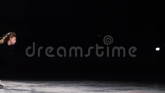 一个穿着黑色西装的职业滑冰运动员在冰上以燕子的姿势单腿旋转视频的预览图
