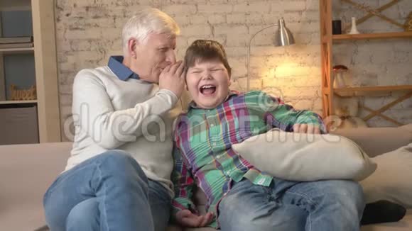祖父在孙子耳边低语一个有趣的秘密八卦小胖小子笑了家庭舒适家庭舒适视频的预览图