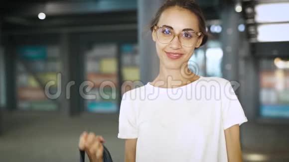 年轻的微笑时尚的美女戴着透明的眼镜摆在户外慢动作视频的预览图