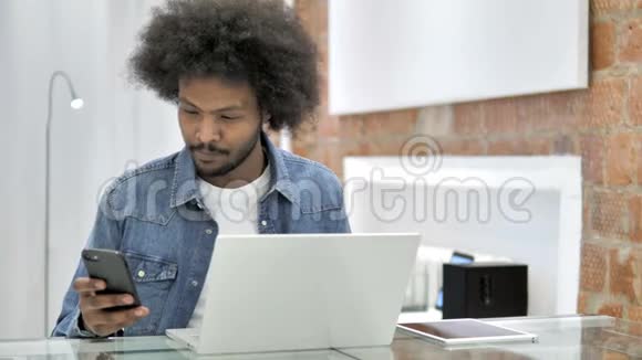 使用智能手机和笔记本电脑的非洲男人视频的预览图
