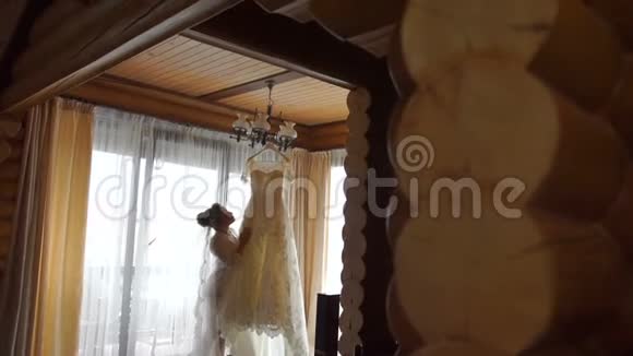 年轻可爱的金发新娘的完整视野触摸和享受她优雅的婚纱挂在上面视频的预览图