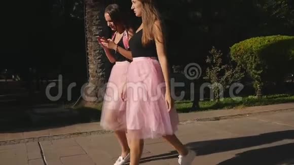 两位穿着薄纱裙和运动鞋的年轻美女在户外散步视频的预览图