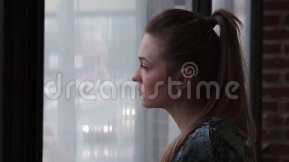 一个年轻悲伤的女人向窗外看视频的预览图