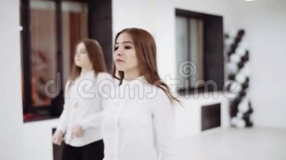 两个穿着白色衬衫和黑色裤子的女孩在镜子前跳舞视频的预览图