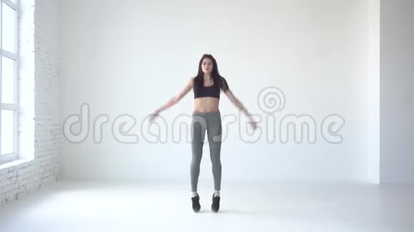 做热身运动活泼的女人在白色的工作室里跳跃和举手4k视频的预览图