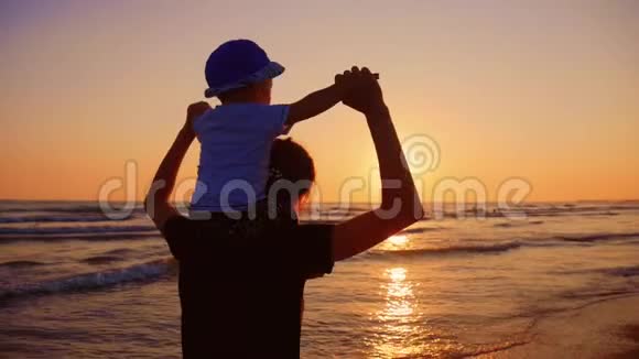 母亲和小儿子在日落时在海滩上散步和玩耍视频的预览图