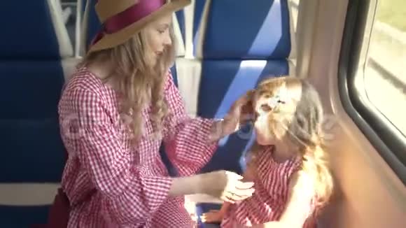 美丽的妈妈和可爱的女儿坐在火车的车窗前玩蛋糕视频的预览图