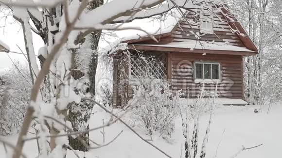 白雪覆盖的冬林中的小木屋照相机的缓慢水平移动视频的预览图