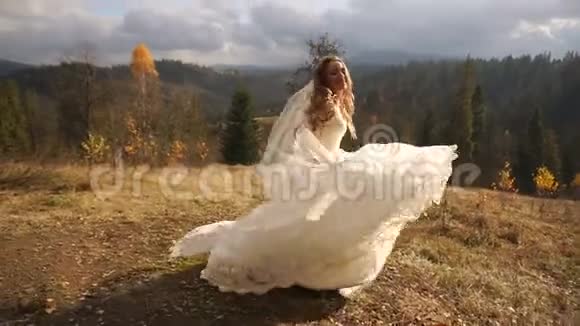 迷人的有趣的新娘穿着华丽的衣服在金色的山脉中跳舞和跳跃的时候玩得很开心视频的预览图