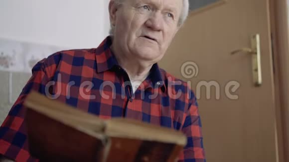 有皱纹的老人在房间里读着思考的书4K视频的预览图