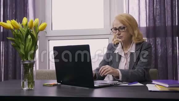在办公桌上工作的高级女性视频的预览图
