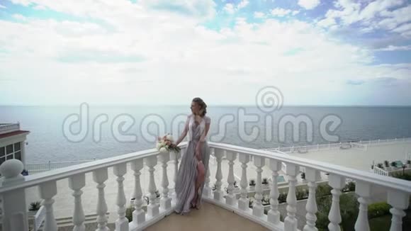 年轻的金发女子穿着内衣在露台上摆着新娘花束海景视频的预览图