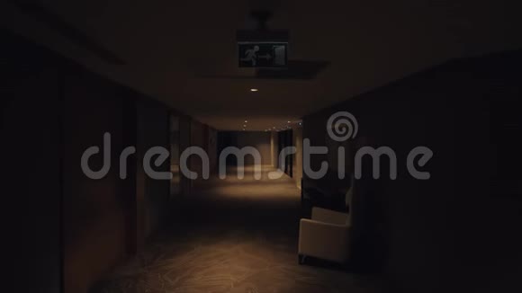 在酒店走廊漫步在昏暗的灯光下观看视频的预览图
