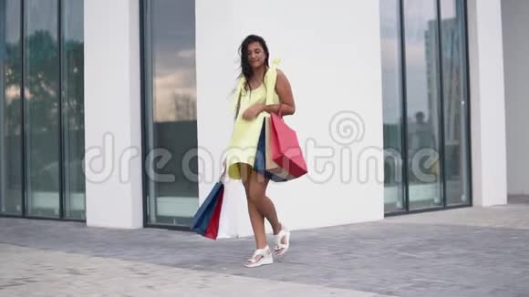漂亮的女孩模特购物后手里拿着彩色的袋子慢动作高清高清视频的预览图