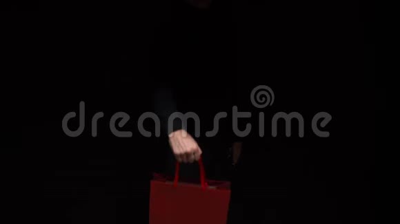 手拿包裹在黑色背景上复制空间购物销售折扣视频的预览图
