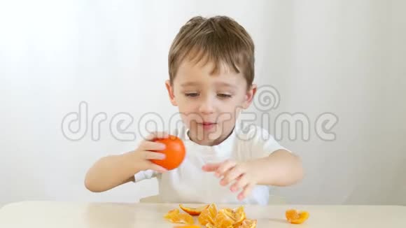 玩橘子的孩子快乐的孩子坐在桌子旁双手把橘子涂在眼睛上视频的预览图