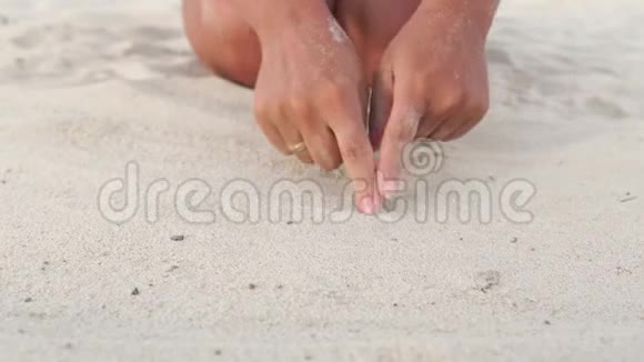 在沙滩上吸引心的女人特写女手指在夏日沙滩上画心慢动作爱情视频的预览图