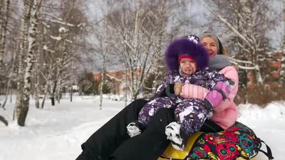 快乐的妈妈和女儿在冬天的雪中雪橇玩雪球母亲和孩子笑着快乐地在视频的预览图