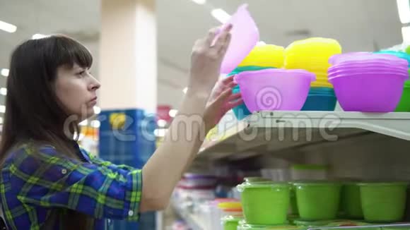 一个年轻的女人选择并在超市买了一个塑料碗视频的预览图